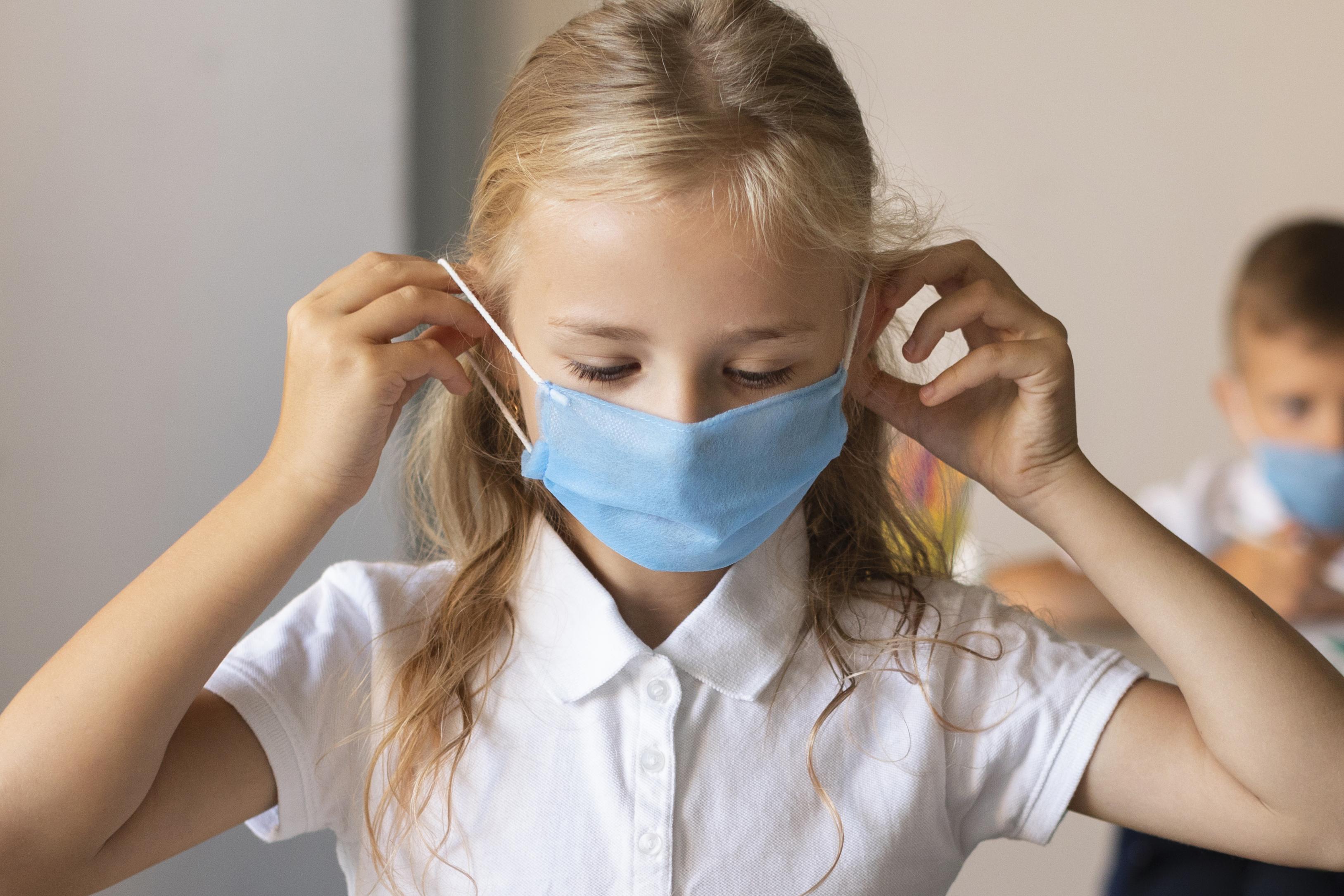 front-view-little-girl-putting-face-mask.jpg