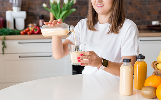 happy-brunette-woman-sitting-with-bottle-smoothie-fruits-home-kitchen-vegan-meal-detox-concept-girl-with-white-tshirt-drinking-fresh-cocktail-mockup-packaging.jpg